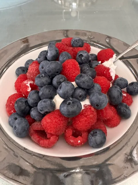 Himbeeren und Heidelbeeren auf einem weißen Milchprodukt